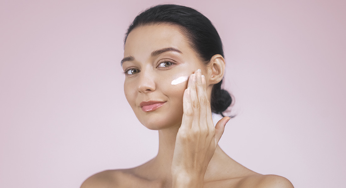 девушка наносит крем на лицо