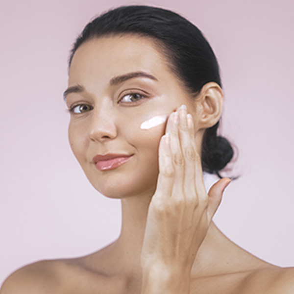 девушка наносит крем на лицо
